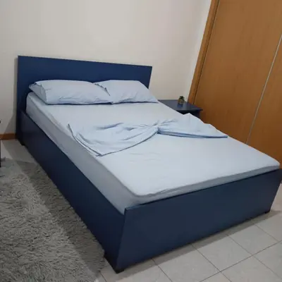 a bed with a blue headboard and white sheets at ManubelaRelax in Praia