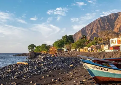 a boat sitting on a rocky beach next to the ocean at ANGÉLICA RÉSIDENCE Centre-ville 350 m plage in Tarrafal