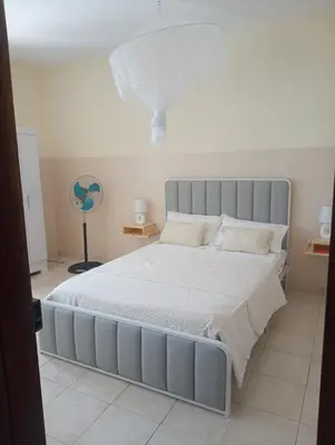 a bedroom with a large bed with white sheets and pillows at ANGÉLICA RÉSIDENCE Centre-ville 350 m plage in Tarrafal