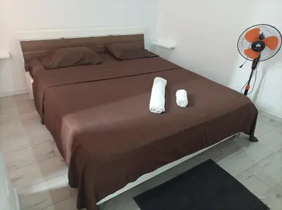 a bed with two white towels and a fan at LBranco in Porto Novo
