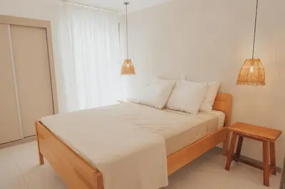 a bedroom with a bed with white sheets and a table at Laginha Apartment in Mindelo