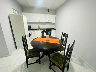 a kitchen with a table and chairs and a refrigerator at Apartamento T2 mobiliado in Mindelo