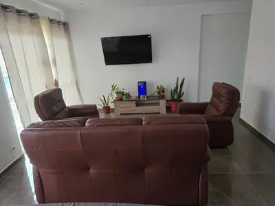 a living room with a brown couch and two chairs at Apartamento Inteiro Porto Novo Abufador in Porto Novo