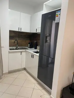 a kitchen with white cabinets and a black refrigerator at Larriba Santa Maria by RPG Group in Santa Maria