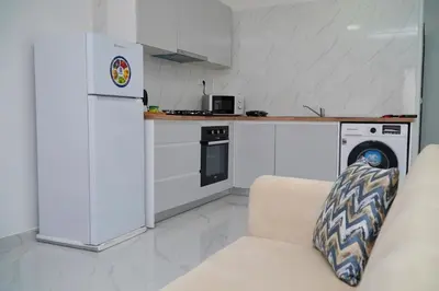 a kitchen with a couch and a white refrigerator at Comfortable 1-bedroom 400 meters from the beach with Fast Wi-Fi in Santa Maria