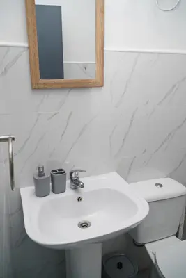 a white bathroom with a sink and a mirror at Comfortable 1-bedroom 400 meters from the beach with Fast Wi-Fi in Santa Maria