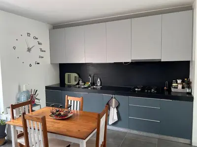 a kitchen with white cabinets and a wooden table at City View Apartment in Praia
