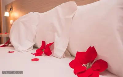 a white bed with red flowers on it at Hotel Cesaria in Praia