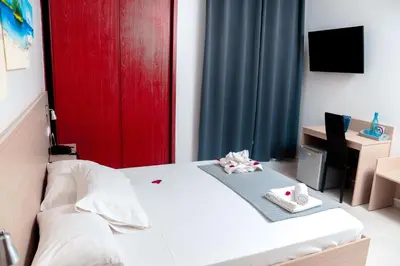 a bedroom with a white bed and a red door at Hotel Cesaria in Praia