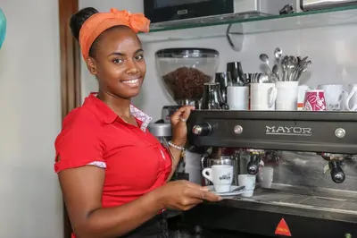 a woman standing in a kitchen with a coffee machine at Hotel Cesaria in Praia
