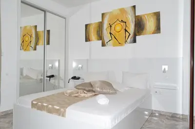 a white room with a bed and paintings on the wall at Hotel Cesaria in Praia