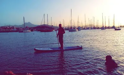 a person standing on a paddle board in the water at Arla Residential in Mindelo