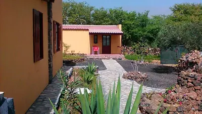 a garden with a house and a red chair at Coin de Paradis,Pavillon Doucimar in Porto Novo