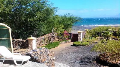 a white chair sitting on a stone path near the beach at Coin de Paradis,Pavillon Doucimar in Porto Novo