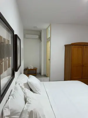 a bedroom with a bed with white sheets and pillows at Pousada Praia Maria in Praia