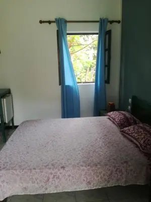 a bedroom with a bed and a window with blue curtains at Aldeia Jerome in Paul