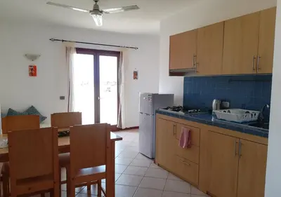 a kitchen with a table and a refrigerator and a table and chairs at Pedra do Sol Praia Estoril Sal Rei FREE WI-FI in Sal Rei