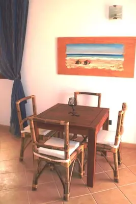 a wooden table with two chairs and a painting on the wall at Holiday Properties Oleandro Ocean in Santa Maria