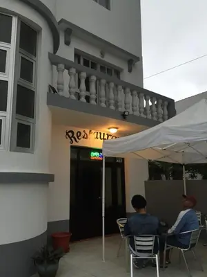 two people sitting under an umbrella in front of a building at Hotel Cruz Grande-Brava in Vila Nova Sintra