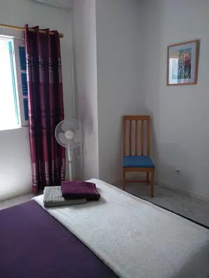 a bedroom with a bed and a chair and a window at Maderalzinho in Mindelo