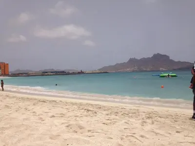 a person standing on a beach with the ocean at Maderalzinho in Mindelo