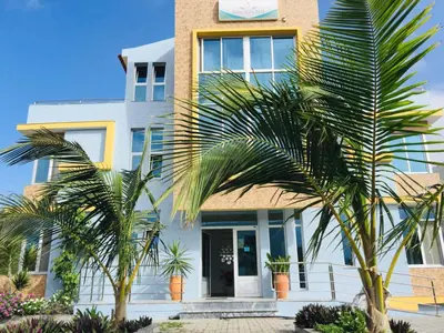 a building with palm trees in front of it at Vista Mar in Tarrafal
