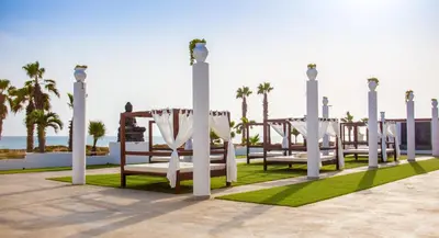 a row of benches with a wedding altar on the beach at Hotel LIVVO Budha Beach in Santa Maria