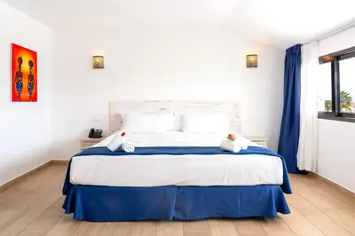 a bedroom with a large bed with blue curtains at Hotel LIVVO Budha Beach in Santa Maria