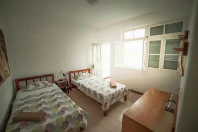 a bedroom with two beds and a table and a window at Música do Mar in Ponta do Sol