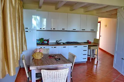 a kitchen with white cabinets and a wooden table at Porto Antigo Hotel BB in Santa Maria