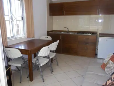 a kitchen with a wooden table and white chairs at Basic Hotel in Mindelo