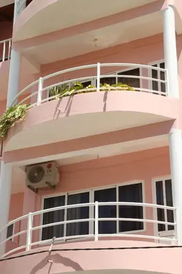 a pink apartment building with a balcony at Restaurante Residencial Nova Cidade in Porto Novo