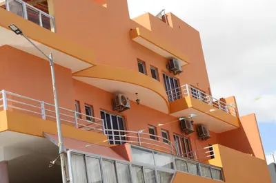 an orange building with balconies on the side of it at Restaurante Residencial Nova Cidade in Porto Novo