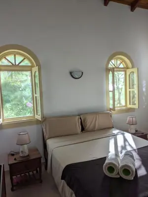 a bedroom with a bed with two windows and two shoes at Torre Sabina in Vila do Maio