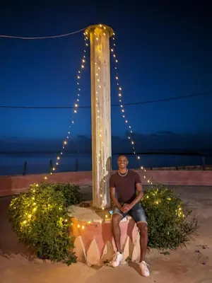 a man sitting next to a pole with lights at Torre Sabina in Vila do Maio