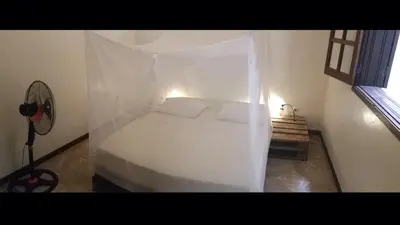 a bedroom with a white bed with a mosquito net at Private Holiday Apartment in Tarrafal