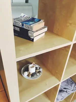 a shelf with a stack of books and a candle on a plate at My Place Apt#1 in Praia