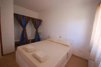 a bedroom with a white bed with two towels on it at Villa Maris Ecolodge in Morro