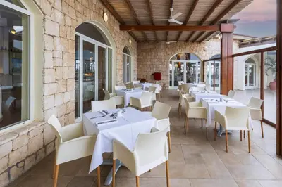 a restaurant with white tables and white chairs at Occidental Boa Vista Beach in Rabil