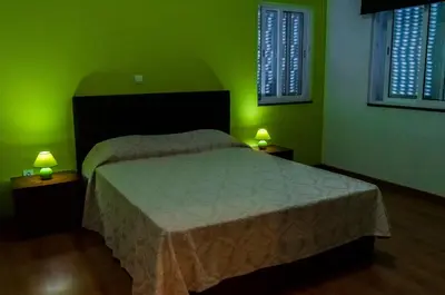 a bedroom with green walls and a bed with two lamps at Casa Sams in Paul
