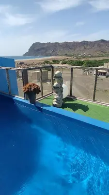 a blue swimming pool with a view of the ocean at Pousada B&B Le Gourmet in São Pedro