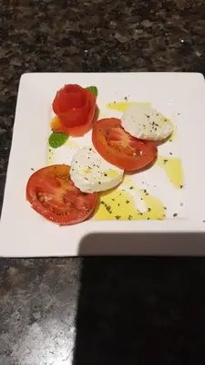 a white plate with tomatoes and cheese on it at Cote de France in Fundura