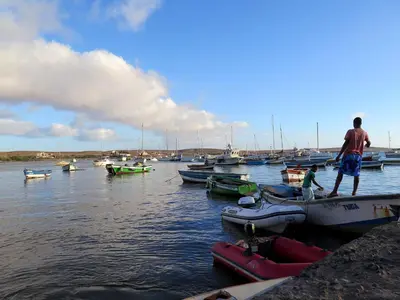 two men standing on a dock with boats in the water at Yacht Club Sal in Palmeira