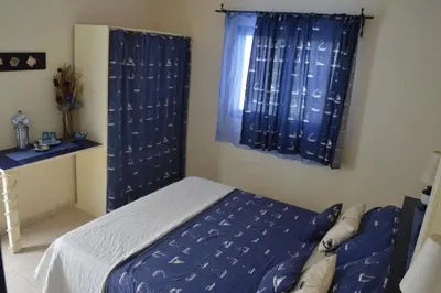 a bedroom with a bed and a window with blue curtains at Yacht Club Sal in Palmeira