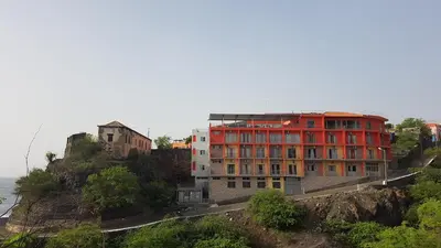 a red building on a hill next to the ocean at Hotel Ocean View & Restaurante Seafood in São Filipe