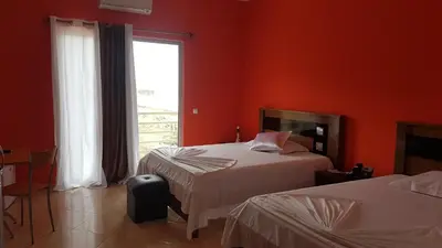 two beds in a room with red walls and a window at Hotel Ocean View & Restaurante Seafood in São Filipe
