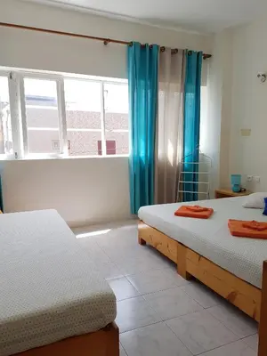 a bedroom with two beds and a window with blue curtains at Casa D'Mar in Ponta do Sol