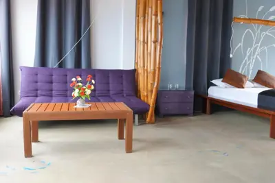 a living room with a purple couch and a table at kasa Tambla in Ponta do Sol