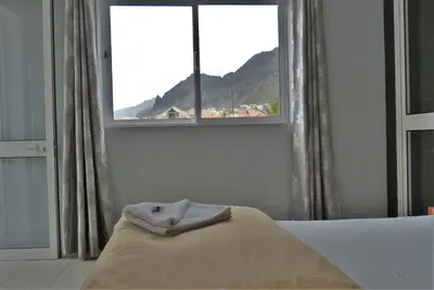 a bedroom with a bed and a window with a mountain at kasa Tambla in Ponta do Sol