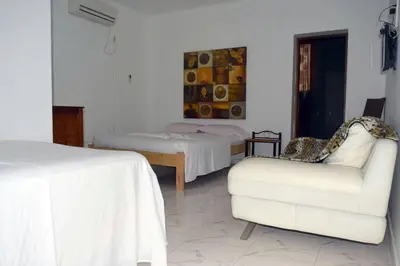 a bedroom with two beds and a couch and a chair at Hotel Miramar Fogo Brava in São Filipe